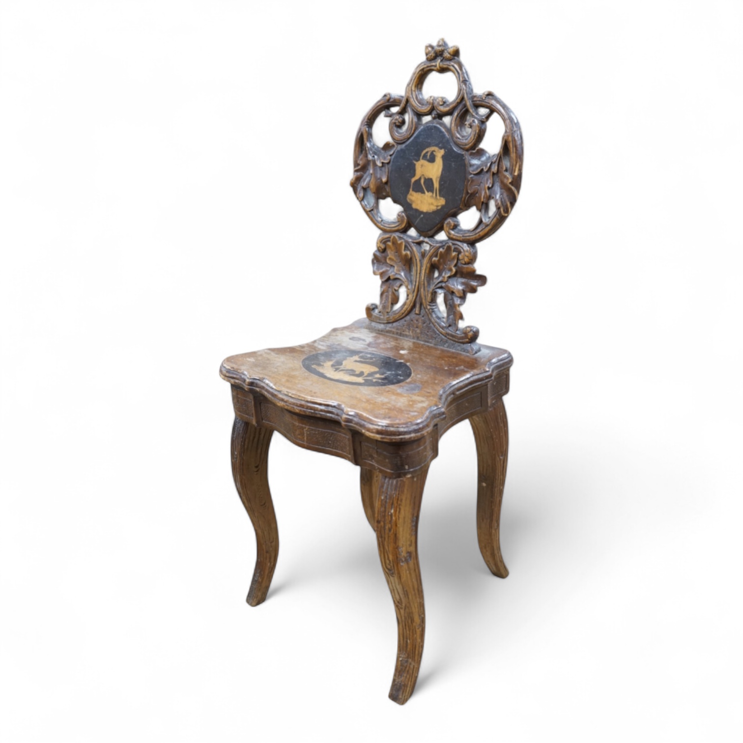A 19th century Black Forest carved child’s musical chair with integral music box, the seat and back each inlaid with an animal cartouche, 68cm high